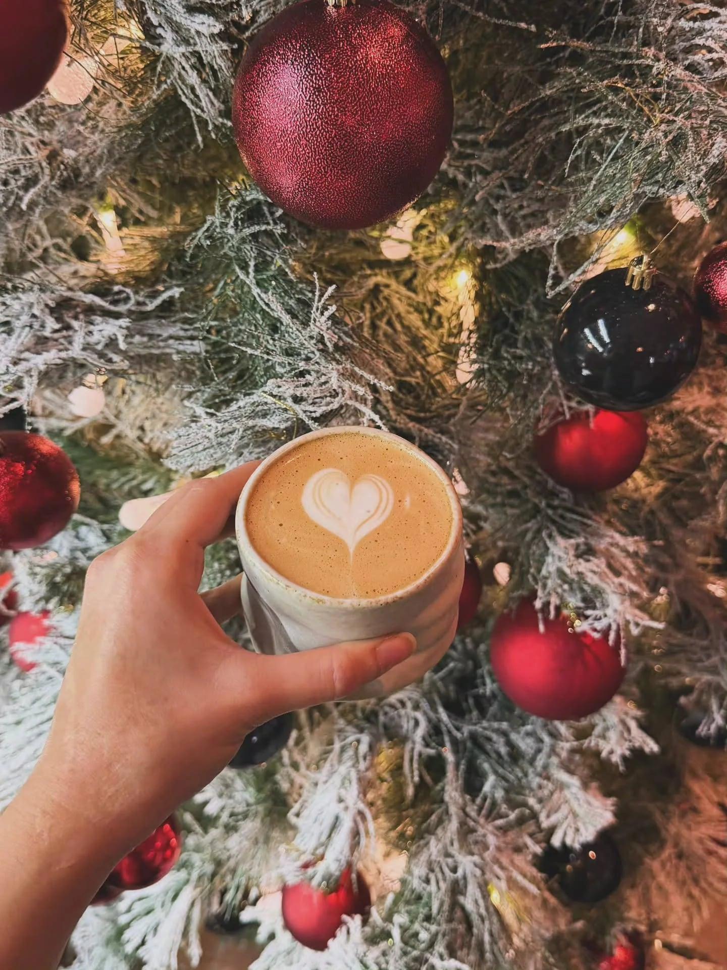 Cappuccino mit Latte Art in einer Bali-Tasse vor dem Weihnachtsbaum